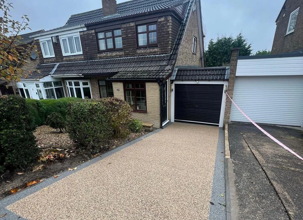 Natural-toned resin driveway beside a planted front garden